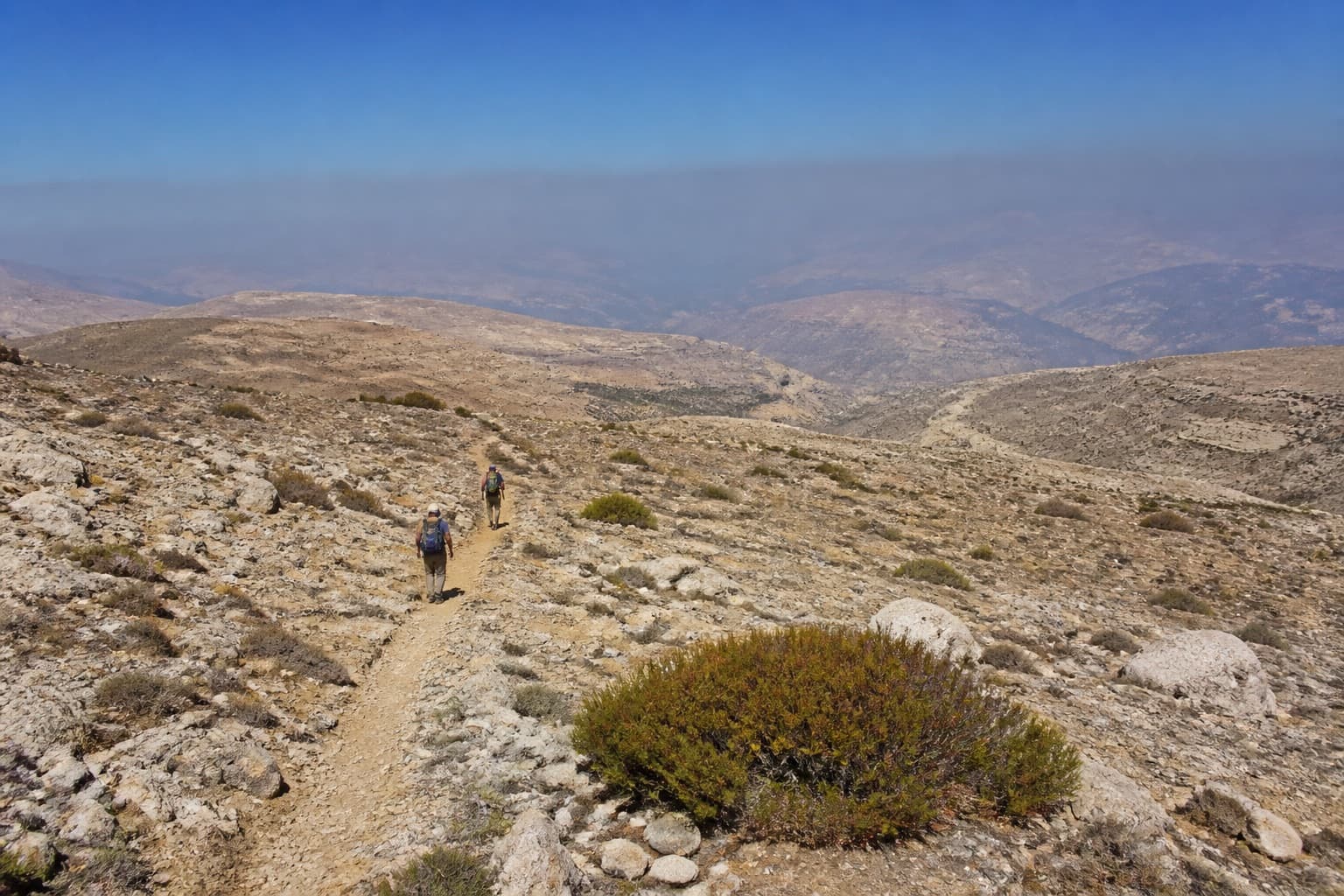 Hikers on a limestone plateau trail in the mountains above Faqra